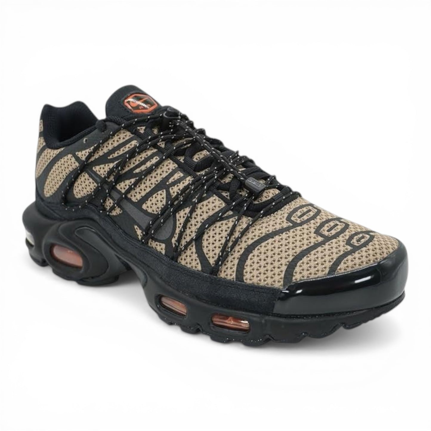 Nike Air Max Plus sneakers in tan with black tiger stripe pattern, black overlays, and laces. Tuned Air cushioning.