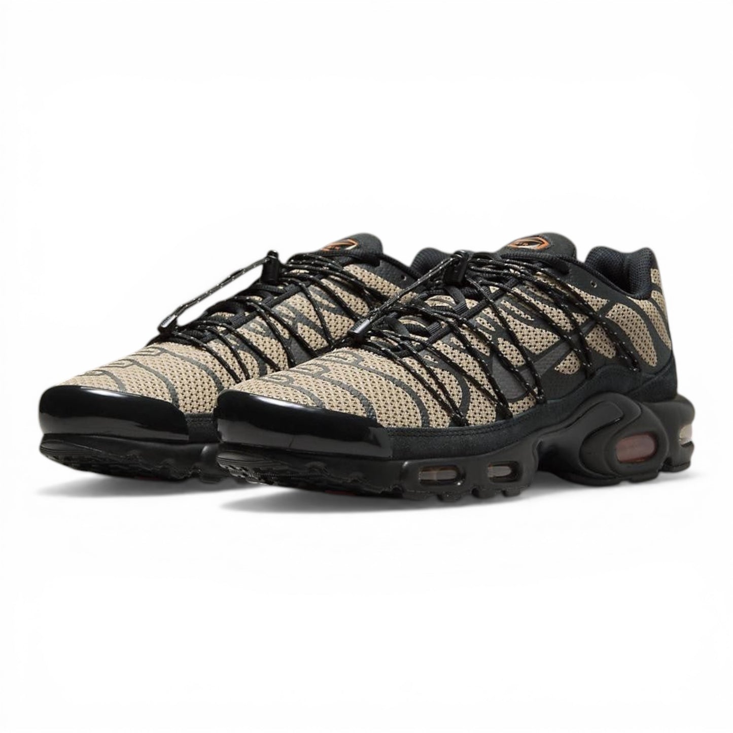 Nike Air Max Plus sneakers in tan and black tiger-stripe mesh with black overlays and laces. Tuned Air cushioning.