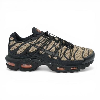 Nike Air Max Plus sneakers in tan and black tiger-stripe mesh with black overlays and orange air cushioning.